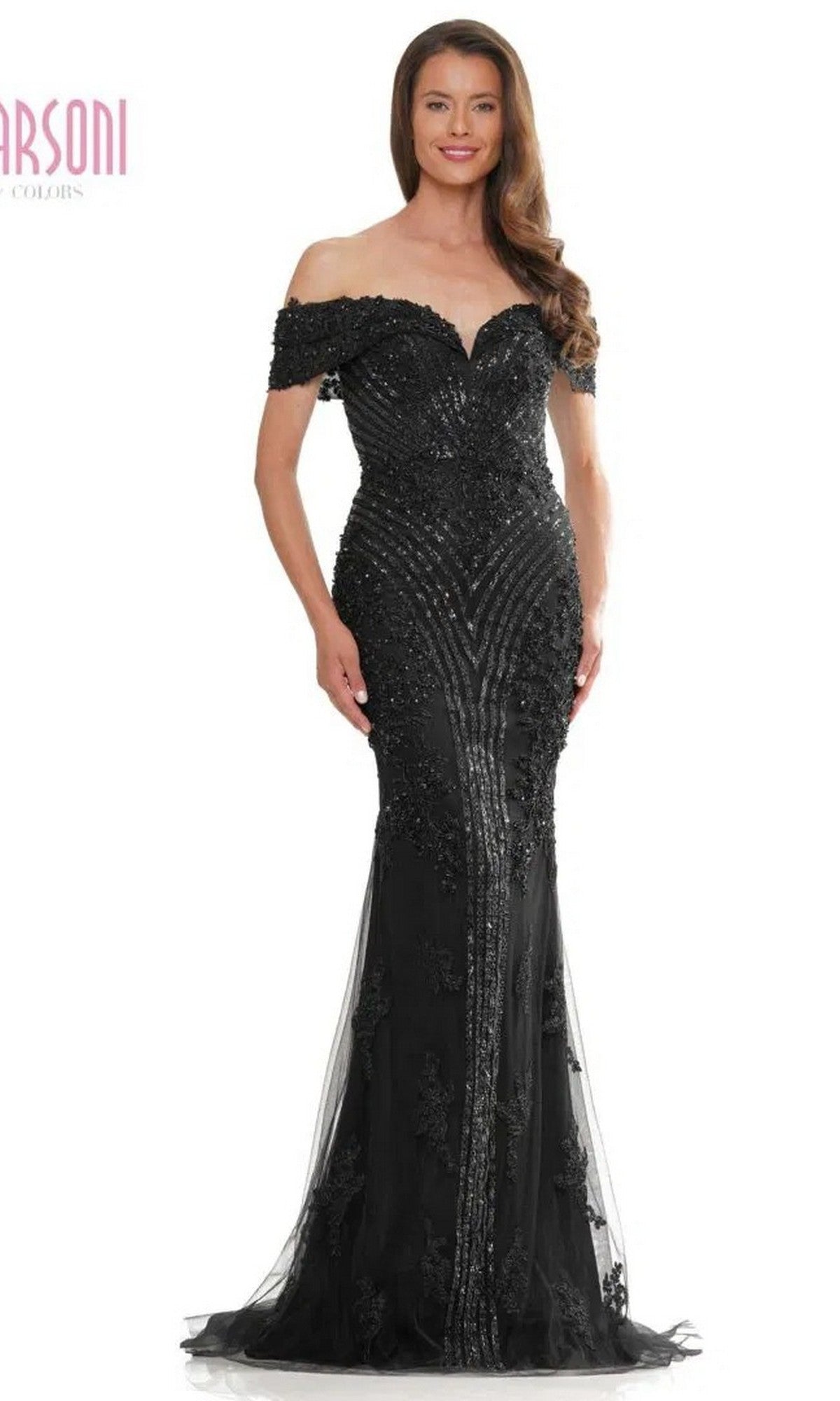 A woman stands smiling in a black Marsoni MV1275 long formal dress with off-the-shoulder design, featuring intricate lace and beaded details.
